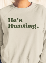 Load image into Gallery viewer, Stay cozy and stylish this season with our tan "He’s Hunting" sweater! Crafted from our Laviva Sport Soft material, this comfy piece not only keeps you warm but also answers that dreaded question of where your significant other is. With the Muscadine Ridge logo gracefully running down the right sleeve, you’ll showcase your love for the outdoors while looking effortlessly chic. Perfect for those crisp days out or lounging at home, this sweater is a must-have for every hunting enthusiast's partner. Grab yours