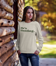 Load image into Gallery viewer, Stay cozy and stylish this season with our tan "He’s Hunting" sweater! Crafted from our Laviva Sport Soft material, this comfy piece not only keeps you warm but also answers that dreaded question of where your significant other is. With the Muscadine Ridge logo gracefully running down the right sleeve, you’ll showcase your love for the outdoors while looking effortlessly chic. Perfect for those crisp days out or lounging at home, this sweater is a must-have for every hunting enthusiast's partner. Grab yours